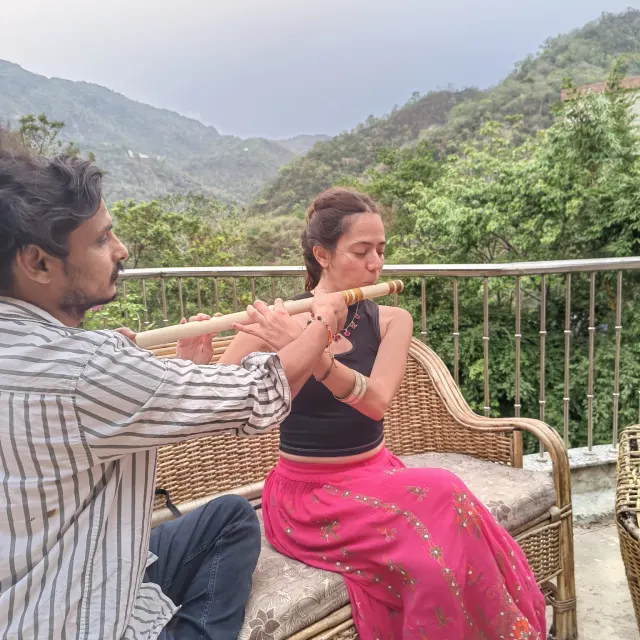 Kamal Negi teaching bansuri flute technique on the studio balcony overlooking the Rishikesh hills